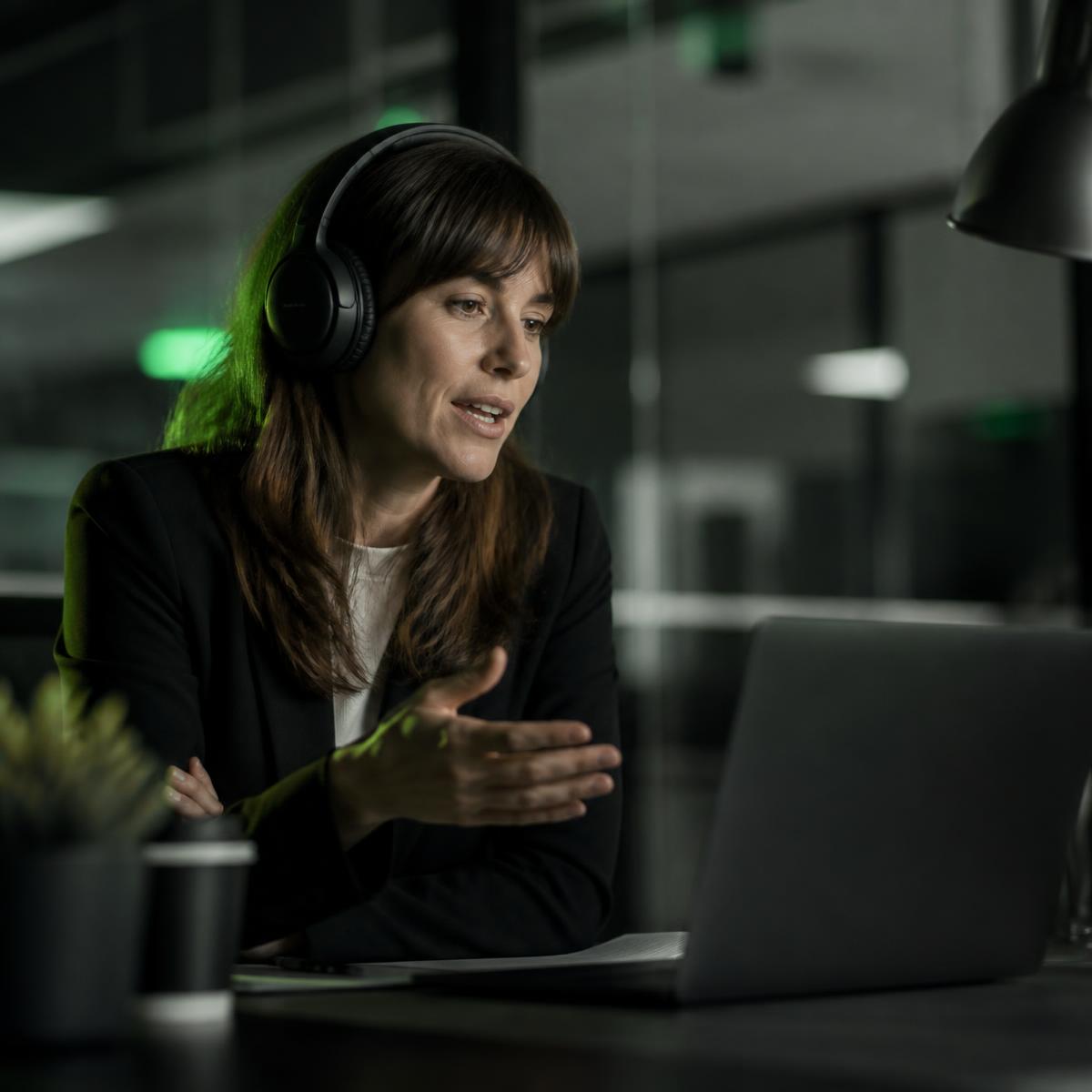 Recruiter wearing headphones speaking with a candidate during a voice interview in a dim office